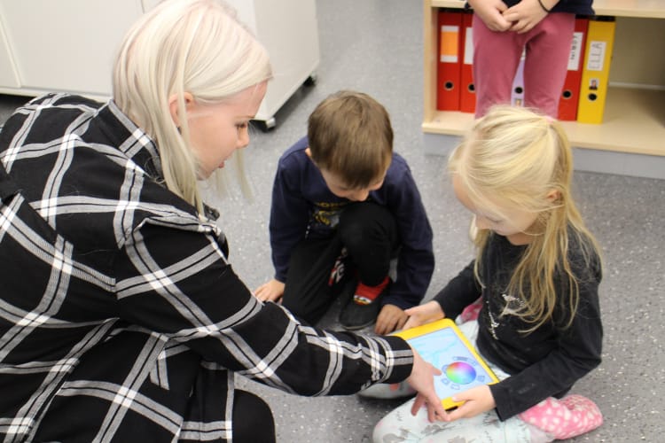 Lukiolainen opastaa kahta eskari-ikäistä iPadin äärellä.